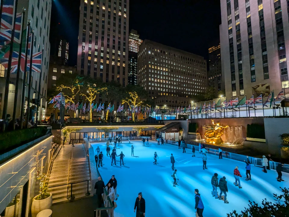 Ice rink lit in blue between buildings at night.