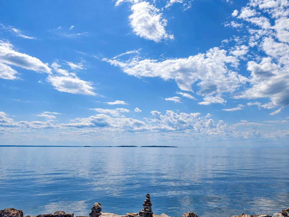 Blue sky and white clouds over a wide stretch of water.