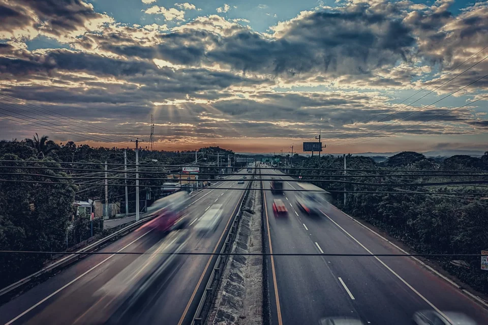 An avenue seen from above under a sky of clouds at dawn.