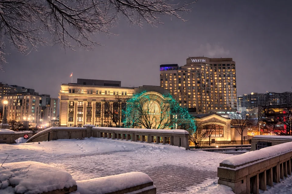 Snowy square at dusk with lit buildings and a dome decorated with lights.