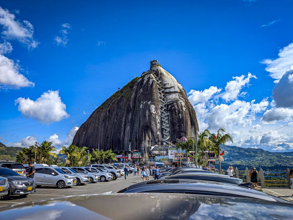 Huge rock formation beside a town under a blue sky.