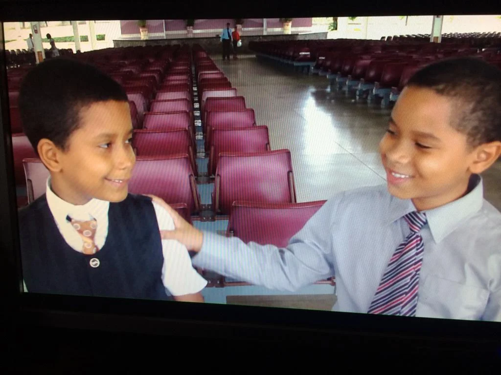 Jonás and his best friend as kids, in front of rows of seats