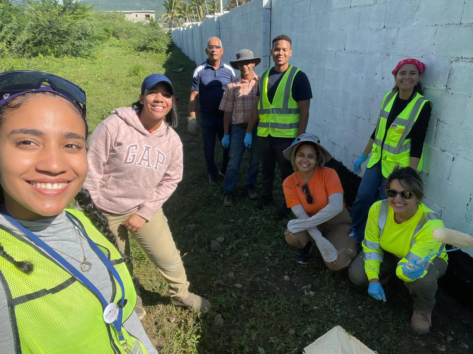 Volunteers next to a wall, several in work vests