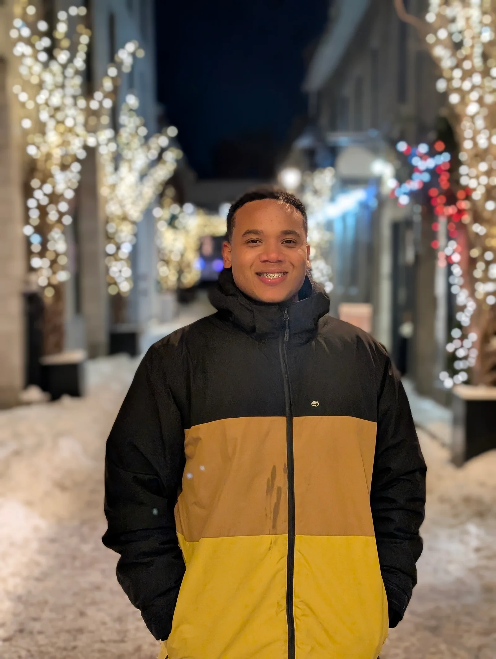 Jonás Javier Encarnación, full-stack developer and UX/UI designer, smiling in a coat with lights behind him